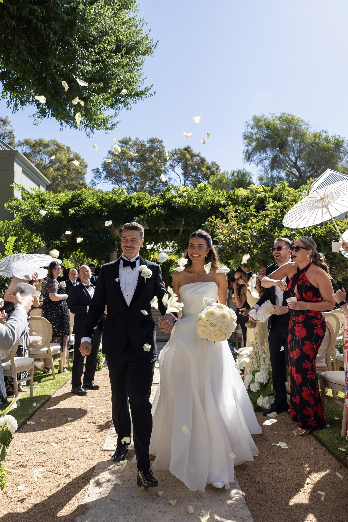 Newlyweds walking back up the aisle through falling petals