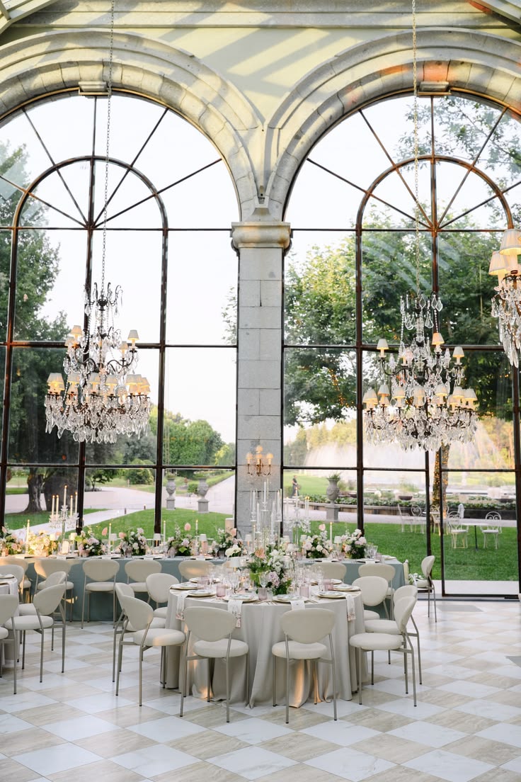 Round tables set for a reception in a glass orangery